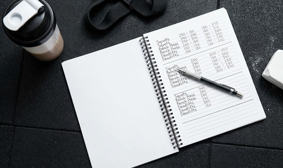 Athlete using a gym logbook to track progressive overload